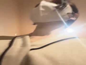 Video of a person wearing a white face mask and a light-colored shirt, slightly blurry, with a bright light source in the background, creating a soft halo effect.