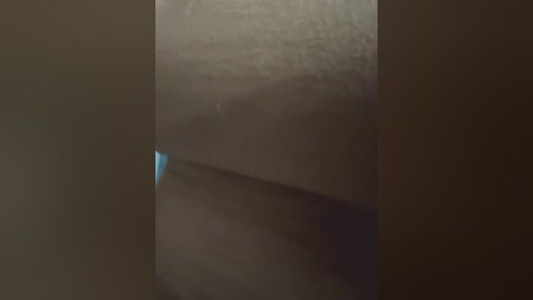 Media: A video of a close-up, textured surface with a faint, small blue light at the bottom center, creating a stark contrast against the dark, shadowy background.