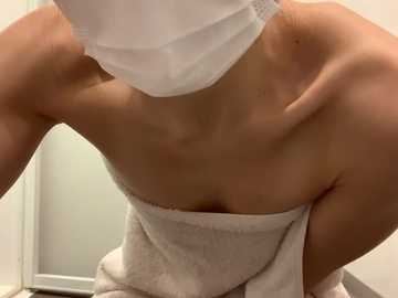 Media: A close-up video of a person with a white surgical mask and towel wrapped around their shoulders, covering their chest. The person's face is not visible. The background is a plain, off-white wall.