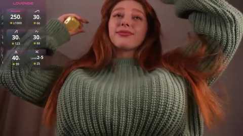 Video of a young woman with long, red hair, wearing a green knitted sweater, flexing her arm, with a virtual fitness app interface overlaying the image.