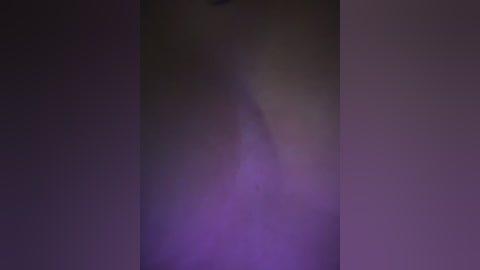 A blurred video showing a dark-skinned woman with long, flowing hair, partially obscured by shadows, standing in a dimly lit room. The background is a mix of purple and dark tones, creating a moody atmosphere.