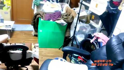 A video of a cluttered office with a green chair, a black office chair, a brown chair, and a desk covered in papers and clothes. The image includes Korean text in the bottom right corner.