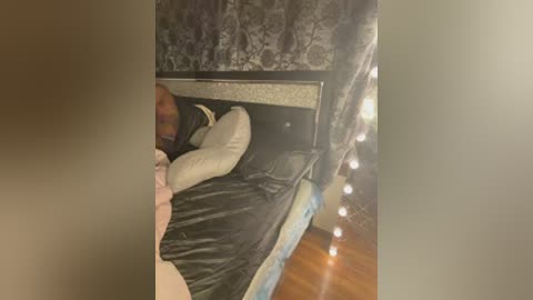 Video of a dimly lit bedroom with a bunk bed, covered in black and white bedding, featuring a person's legs and feet partially visible.