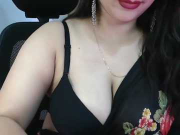 Media: Video of a light-skinned woman with long dark hair, wearing a black bra with floral embroidery, sitting in a car. She has a slim build, fair skin, and wears dangling earrings.