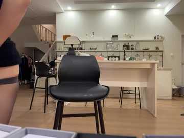 Video of a modern, minimalist kitchen with white cabinets, stainless steel appliances, and a black barstool in the foreground.