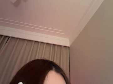 Video of a ceiling fan in a beige room with light brown curtains. A person with long, dark hair is partially visible in the lower part of the image.