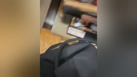 A blurred video of a person in a dark jacket standing on a wooden floor, possibly in an office setting, with a partially visible person in the background.
