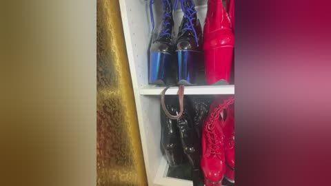 Video of a cluttered closet shelf displaying a mix of black, blue, and red high-heeled shoes, with a metallic gold and brown wall visible on the left.