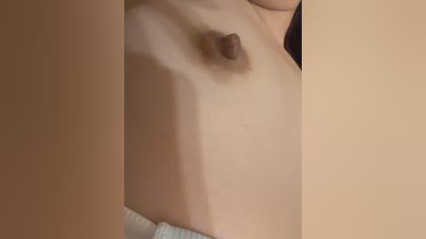 Video of a light-skinned, bare-chested woman's torso with small, dark nipples and a textured white towel partially visible at the bottom.