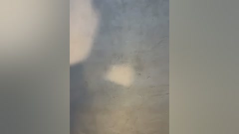 A video depicting a blurred, ethereal image of a human figure with a white aura, standing in a dimly lit, foggy environment. The figure appears translucent, blending into the misty background.