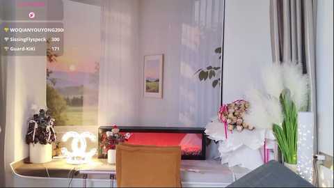 Video of a cozy, minimalist bedroom with a white vanity table, a large mirror, a white chair, and a bouquet of white flowers.