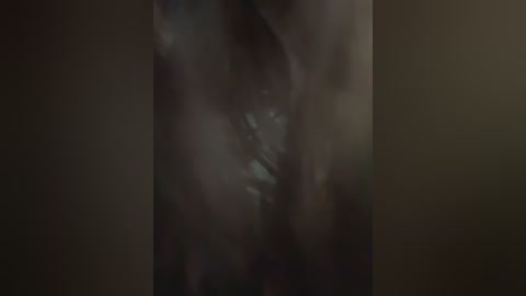A close-up, dark, grainy video of a person's torso, with indistinct features and a blurred background, possibly depicting an intimate scene.