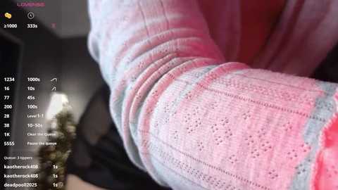 A close-up video of a person\u2019s lower leg in a pastel pink and blue striped knit sock, displaying a 100% completion status on a screen with user names and stats.