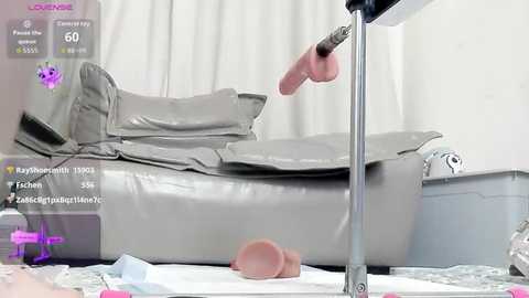 A video of a medical exam room with a gray examination table, a doctor's hand holding a pink, uncircumcised penis, and scattered papers on the floor.