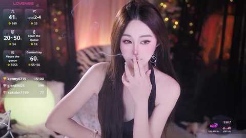 Video of a young Asian woman with long, straight black hair, wearing a black top, holding a cigarette to her lips, set in a dimly lit room with blurred background.