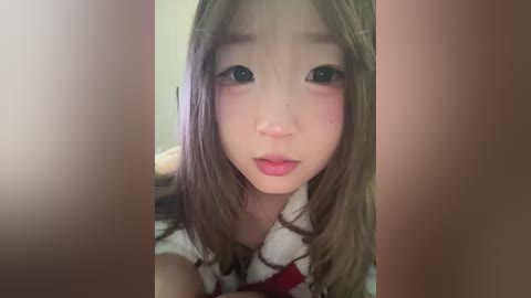 Video of an Asian woman with fair skin, long straight brown hair, and large round eyes, wearing a white and red striped shirt.