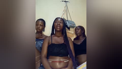 Video of three African women with dark skin, wearing traditional attire and headwraps, sitting indoors.