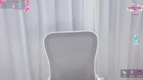 A video of a modern white chair with a cushioned backrest against a backdrop of sheer white curtains. The image has a retro aesthetic, with a pink and purple logo in the top-left corner.