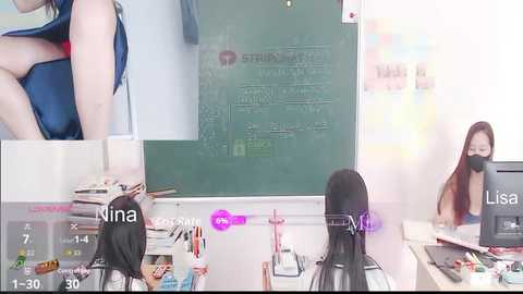 Video of a classroom with a green chalkboard, a teacher wearing a mask, and students in school uniforms. Text overlays show \"Nina\" and \"Lisa\" in the bottom left and right corners, respectively.
