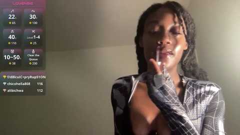 A video of a woman with medium-brown skin, wearing a black and white patterned top, holding a cigarette to her mouth, against a plain, dimly lit background.