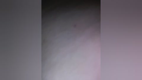 A blurry, monochromatic video of a person's bare, slightly bruised arm, possibly a male, with a light skin tone. The image is dimly lit, featuring a mix of grey and purple hues.