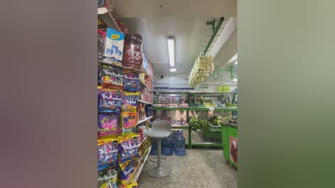 Video of a small, brightly-lit convenience store with colorful candy displays, green shelving, and a central metal stool.