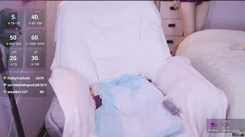 A video of a person lying on a white bed, wearing light blue and white pajamas, in a softly lit bedroom with a white dresser and a nightstand.