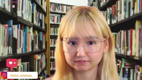 Video of a young Asian woman with straight, shoulder-length blonde hair, wearing glasses, standing in a library with bookshelves filled with colorful books in the background.