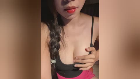 Video of a young Asian woman with light skin, wearing a black bra and pink skirt, holding her breast, partially blurred.