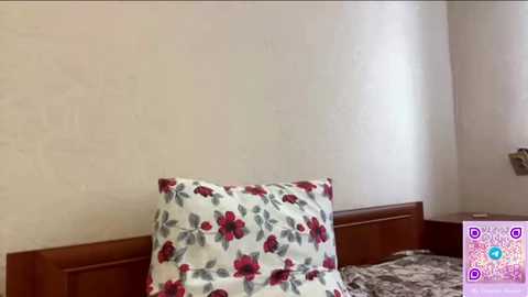 Media: A video of a bed with a floral pillow and a plain pillow against a white wall, featuring a QR code in the bottom right corner.
