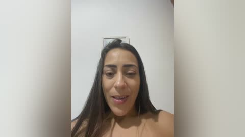 Video of a young, light-skinned woman with long, dark hair, wearing a clear glass frame on her head, against a plain white background.