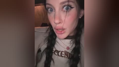 A video of a young woman with fair skin, blue eyes, and dark braided hair, wearing a black choker and a white t-shirt with \"RECENTLY\" printed in bold red letters.