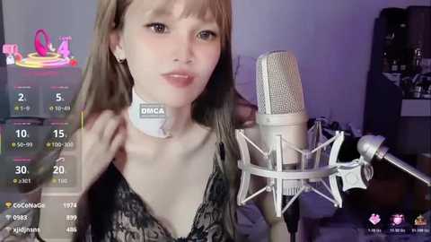 Media: Video of a pale-skinned, long-haired Asian woman in a black lace bra, singing into a microphone. Background features a dimly lit room with a colorful neon sign and various objects.