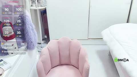 Video of a pink, plush, hand-shaped pillow on a white bed in a tidy, minimalist bedroom with a white wardrobe and a partially visible nightstand with a purple item.
