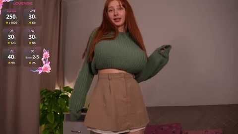 A video of a curvy, red-haired woman in a green sweater and high-waisted shorts, standing in a cozy living room with a plant and floral curtains.