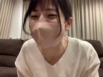 Media: Video of an Asian woman with straight black hair, wearing a beige mask and a white sweater, indoors with beige curtains in the background.