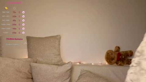 Video of a cozy living room featuring a beige sofa, plush pillows, and a brown teddy bear on a white cushion. Soft, warm lighting creates a serene atmosphere.