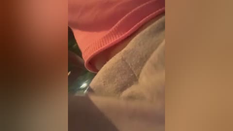 Media: Video showing close-up of a person's torso with a pink shirt and a beige towel, blurry background.