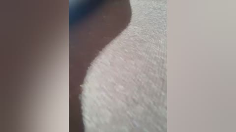 Media: A close-up video of a human thigh with a slightly curved texture, showcasing smooth, light brown skin. The background is blurry, with a faint blue object partially visible in the upper left corner.