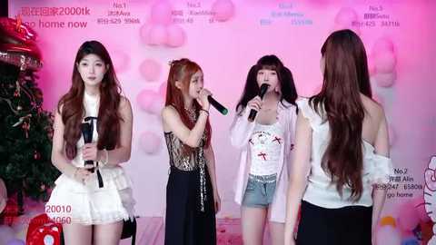 Video of four young Asian women singing into microphones on stage. One wears a white frilly dress, another a black lace top and denim shorts. Background is festive, with Christmas decor and text in Chinese.