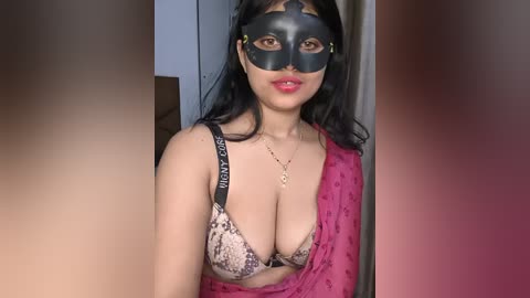 Video of an Asian woman with long black hair, wearing a leopard-print bra and a black masquerade mask, standing indoors with a pink shawl draped over her shoulder.