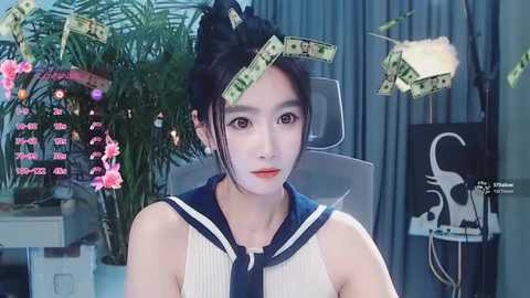 A video of an East Asian woman with fair skin and dark hair in a bun, wearing a traditional Japanese schoolgirl uniform. Money bills are digitally overlaid on her face, creating a surreal effect.