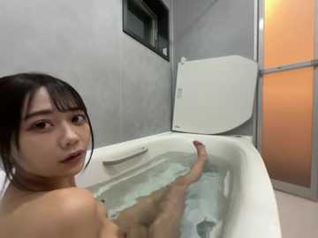 Media: A video of an Asian woman with straight black hair, partially submerged in a white bathtub, in a modern bathroom with gray walls and a partially open shower door.