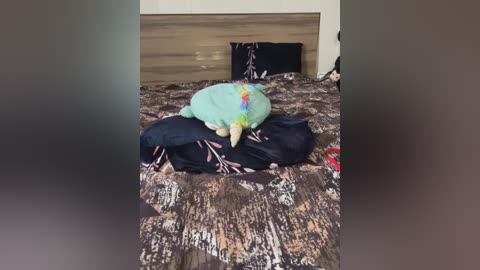 Media: Video of a messy bedroom with a plush toy resembling a dinosaur, a black jacket, and a patterned blanket on a bed. The room has wooden headboard and beige walls.