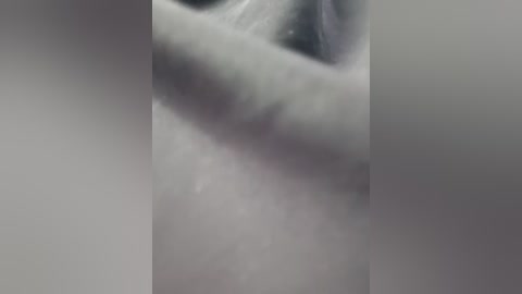 Media: This video captures a close-up view of a woman's face and neck, with blurred edges and a soft, grainy texture. The image has a monochromatic, muted color palette emphasizing shades of gray and white, creating a dreamlike atmosphere.