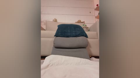 Video of a cozy living room with a white sofa, a teal pillow, and a grey cushion on a recliner, framed by white walls and a wooden floor.