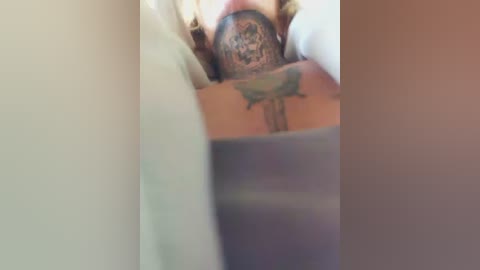 Media: A blurred video of a tattooed arm and hand with intricate designs on the wrist and forearm, partially covered by a grey sleeve.