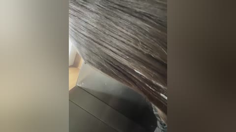 A close-up video of a shiny metallic object, possibly a knife, with a textured, fibrous surface, likely a piece of cloth or plastic, partially wrapped around it. The background is a blurred, neutral-colored room.