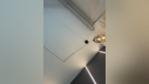 Video of a beige tiled bathroom floor with a black rubber mat and a brass faucet, featuring a close-up view of the faucet's spout and handle.