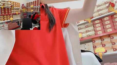 Video of a vibrant red polo shirt with white and yellow trim on a hanger in a well-stocked, organized clothing store.